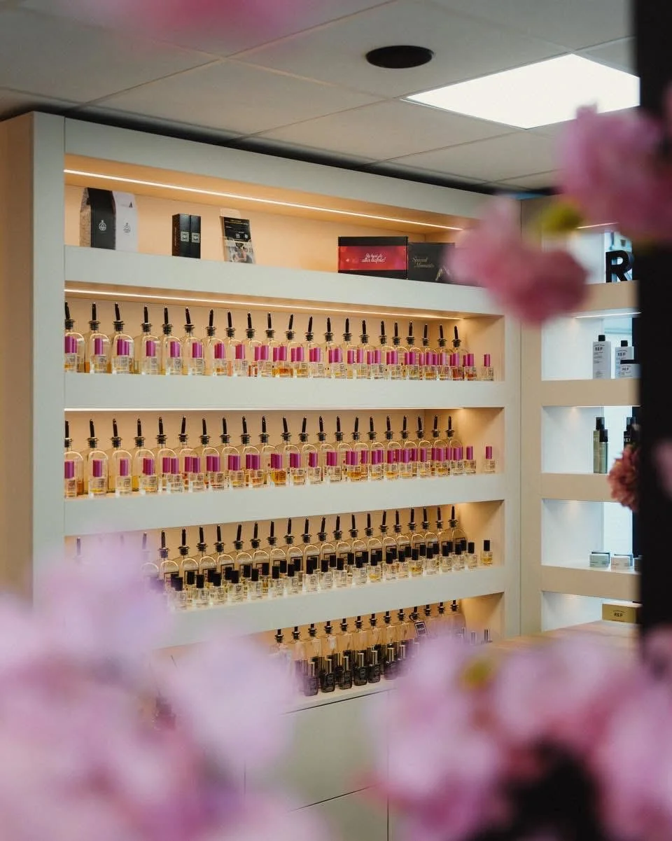 Wand met flesjes hervulbare parfum, gezien door bloesemtakken